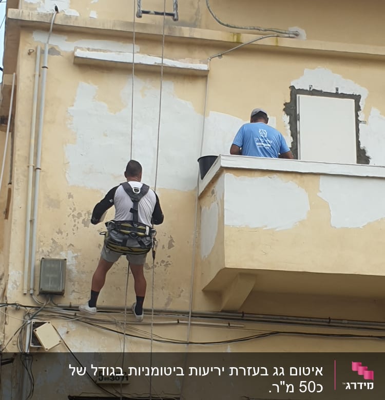 שני אנשים עובדים על איטום קיר חיצוני של בניין